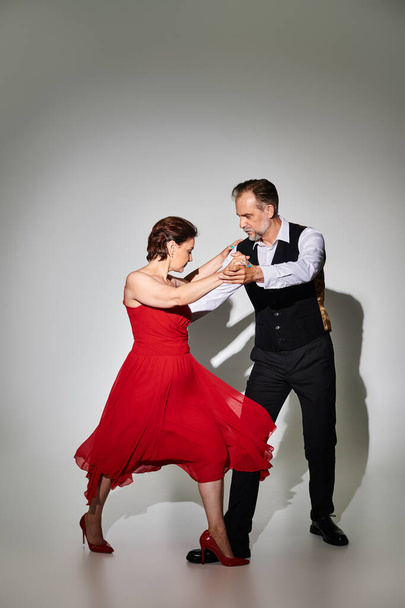 Ballroom dance middle aged couple in red dress and suit dancing tango isolated on grey background - Φωτογραφία, εικόνα