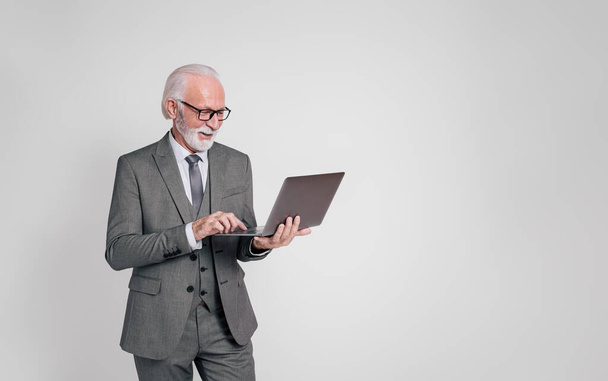 Portrét vysokého mužského výkonného v brýlích pracuje nad notebookem na izolovaném bílém pozadí - Fotografie, Obrázek