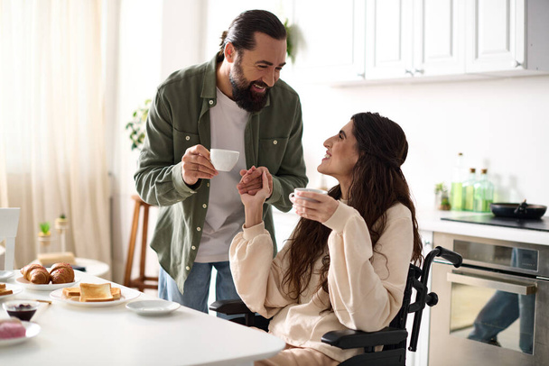 cheerful beautiful disable woman in wheelchair enjoying coffee with her husband during breakfast - Foto, Bild