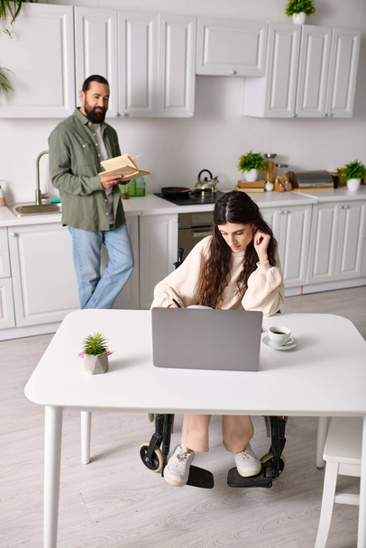 attrayant femme handicapée en fauteuil roulant travaillant de la maison à l'ordinateur portable à côté de son mari de lecture - Photo, image