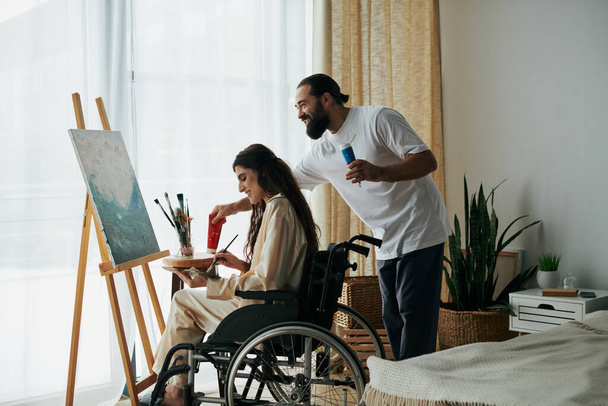 自宅で一緒にイーゼルに絵を描いた 陽気な男と障害のある女性のカップルを大切に - 写真・画像