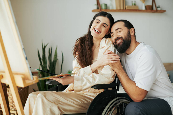 приваблива жінка з малюнком інвалідності на мольберті поруч зі своїм веселим бородатим чоловіком - Фото, зображення