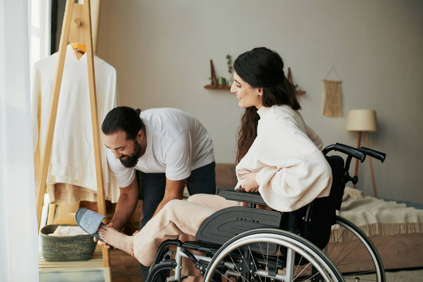 brodaty kochający mężczyzna pomaga jego włącznie żona na wózku inwalidzkim się ubrać podczas gdy w sypialni - Zdjęcie, obraz