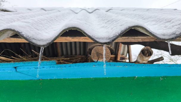 Icicles cuelgan del techo de la casa en invierno. - Foto, imagen