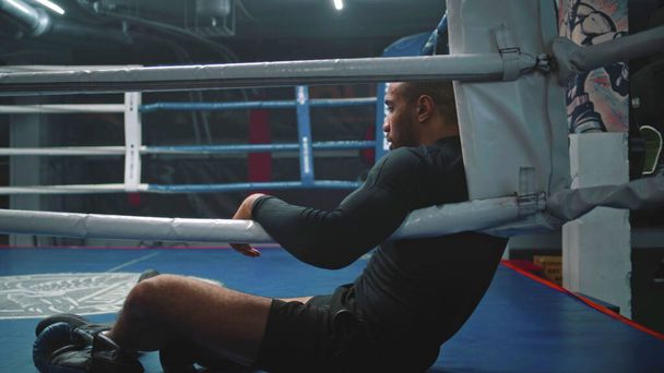 Fáradt és kimerült afro-amerikai bokszoló ül a box ring sarkán. Harcos, izzadsággyöngyökkel az arcán pihenő edzés után. Atléta készül a verseny vagy verseny boksz tornaterem. Közelről.. - Fotó, kép