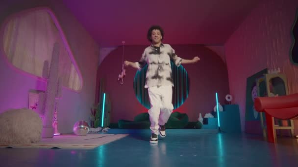 Geniş çekim yavaş çekim genç adam enerjik hip hop dansı yapıyor Stüdyoda moda iç ve neon ışıklı - Video, Çekim