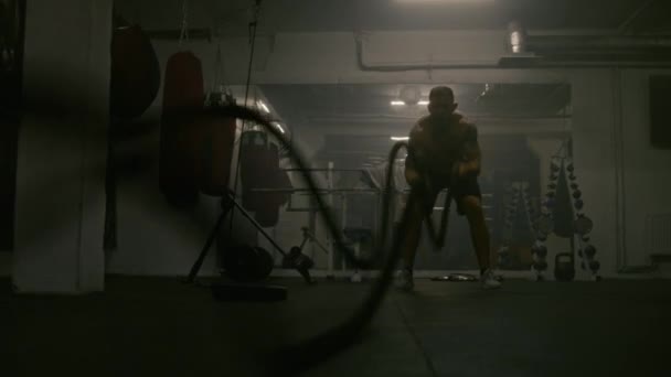 Profesionální mužský boxer dělá kardio nebo vytrvalostní cvičení před mistrovským zápasem. Sportovní cvičení s provazy v tmavé boxerské tělocvičně. Fyzická aktivita a intenzivní výcvik CrossFit. - Záběry, video
