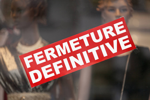 Sinal vermelho em uma vitrine dizendo em francês "Fermeture definitive", significando em inglês "Permanent closure". - Foto, Imagem