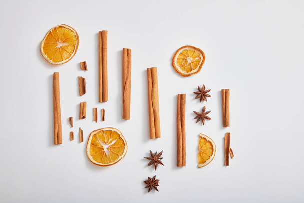 Minimal concept with cinnamon sticks, anise and dried orange slices on white background. Scene for advertising product of herbal extract. Top view, flat lay. - Photo, Image