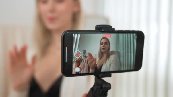Mladý sociální mediální obsah tvůrce žena, aby módní video pomocí selfie hole. Blogger úsměv do kamery a zároveň přesvědčivé on-line oblečení prodávat vlog divákům nebo následovníkům. Blithe - Záběry, video