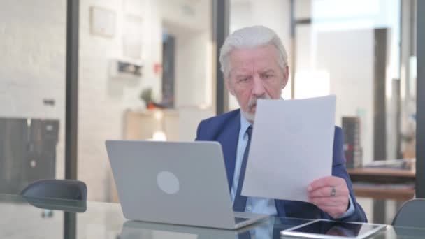 Oude zakenman die zich van streek voelt tijdens het lezen van het contract en het gebruik van laptop - Video