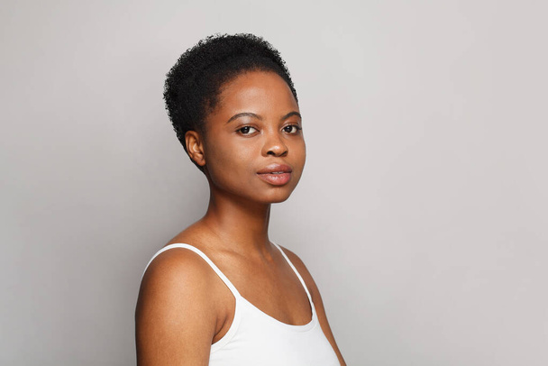 Iloinen terve afrikkalainen amerikkalainen nainen selkeä tuore tumma iho poseeraa harmaalla pohjalla, muoti kauneus muotokuva - Valokuva, kuva