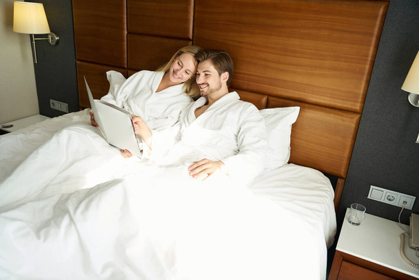 Mutlu yeni evliler yatakta menüyü okuyor, çift kahvaltıyı odada seçiyor. - Fotoğraf, Görsel