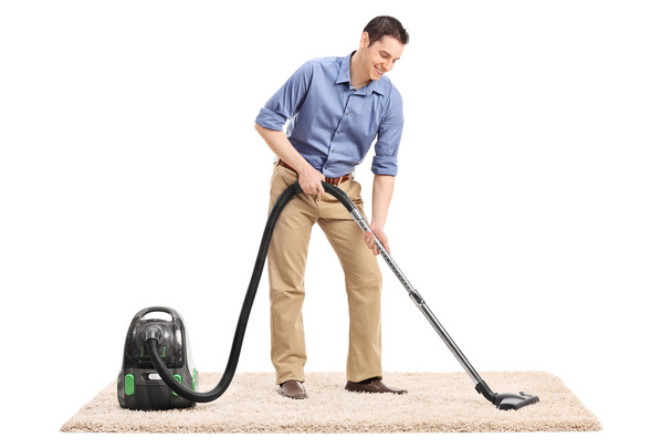 Man cleaning carpet with vacuum cleaner - Foto, afbeelding