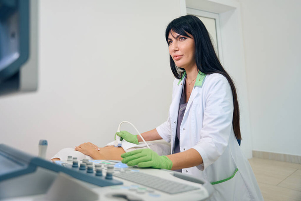 Aikuinen eurooppalainen naisgynekologi tekee ultraäänitutkimuksen raskaana olevalle naiselle klinikalla. Raskauden tutkimisen käsite - Valokuva, kuva