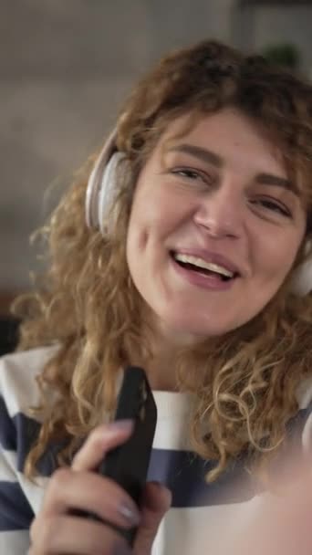 Une femme caucasienne adulte femelle avec écouteurs utilisent un téléphone mobile à la maison pour écouter la musique en ligne sourire heureux chanter joie avoir du plaisir seul espace de copie - Séquence, vidéo