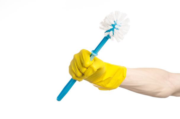 Cleaning the house and cleaning the toilet: human hand holding a blue toilet brush in yellow protective gloves isolated on a white background in studio - Valokuva, kuva