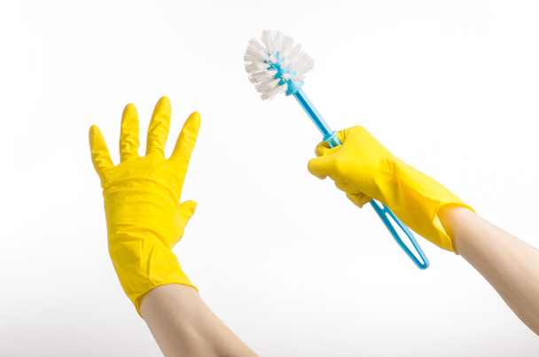 Úklid domu a úklid toalety: lidská ruka držící Modrou toaletní štetku žluté ochranné rukavice izolovaných na bílém pozadí v studio - Fotografie, Obrázek