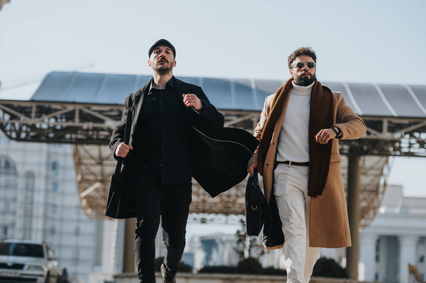 Dos hombres profesionales en ropa de otoño de moda se mueven asertivamente. Una esencia de asociación y estilo en un entorno urbano. - Foto, imagen