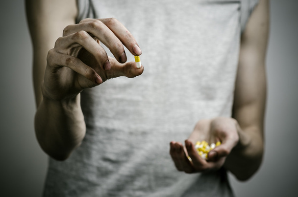 he fight against drugs and drug addiction topic: addict holding a narcotic pills on a dark background - Fotoğraf, Görsel