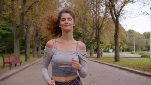 Кавказька щаслива красива бігунка жінка біжить в парку одна вага втратила здорову звичку вранці спортивна жінка тренує кардіо біг спорт на відкритому повітрі в міському парку фітнес біг - Кадри, відео