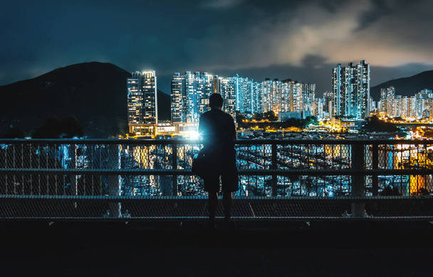 Escena nocturna de silueta de persona frente a rascacielos contemporáneos modernos en Marina con muelles y yates en Aberdeen, Hong Kong - Foto, imagen