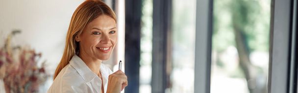 Mujer sonriente empresaria que trabaja en el ordenador portátil, tomando notas en acogedor espacio de coworkign interior - Foto, Imagen