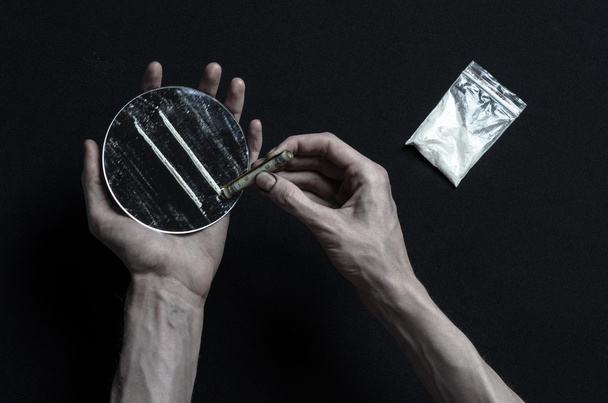 The fight against drugs and drug addiction topic: hand addict lies on a dark table and around it are drugs, a top studio - 写真・画像