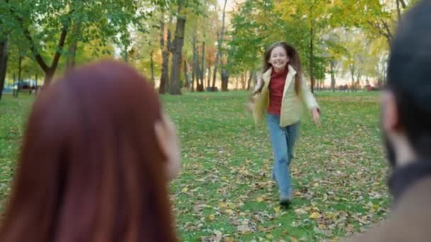 Щаслива мила дівчина мила дівчинка дитина дочка біжить поспішає бігти до батьків тато батько на відкритому повітрі в парку на міських зборах обіймаючи маму тато зв'язуючи сім'ю ласкаве свято весело грати любов - Кадри, відео
