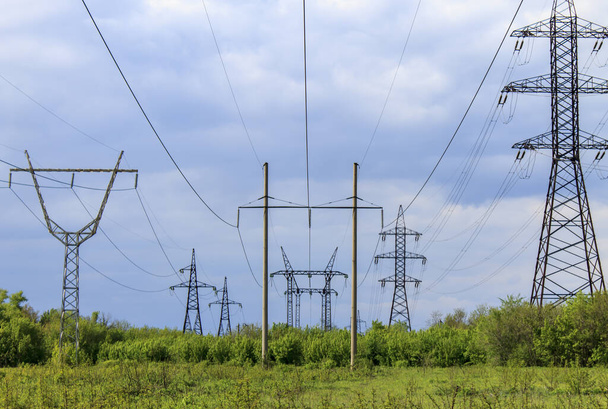 Líneas eléctricas de alto voltaje al aire libre en un campo contra un cielo azul - Foto, imagen