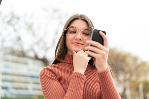 Adolescente ao ar livre pensando e enviando uma mensagem - Foto, Imagem