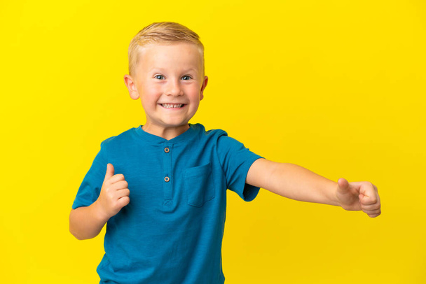 Μικρό ρωσικό αγόρι απομονωμένο σε κίτρινο φόντο δίνοντας αντίχειρες προς τα πάνω χειρονομία - Φωτογραφία, εικόνα