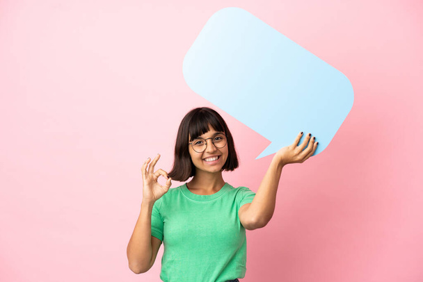 Youing woman holding an empty speech bubble and doing OK sign - Photo, Image