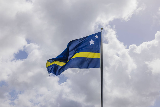 Beautiful view of the Curacao flag waving in the wind against the cloudy sky. - Photo, Image