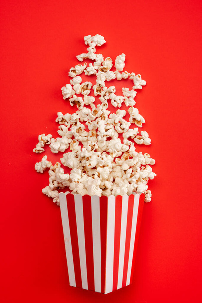 Popcorn en boîte de papier rayé rouge et blanc isolé sur fond rouge - Photo, image