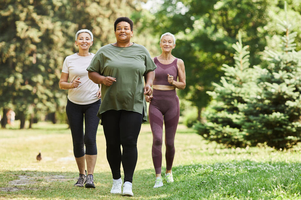 Grupo de mujeres mayores activas corriendo hacia la cámara al aire libre y sonriendo - Foto, imagen