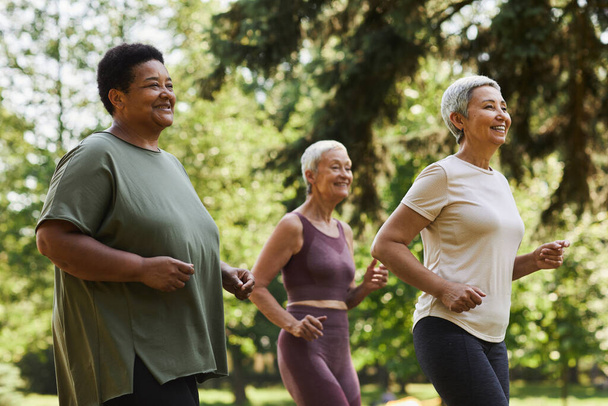 Retrato de vista lateral de mujeres mayores activas corriendo al aire libre en el parque y disfrutando de los deportes - Foto, Imagen