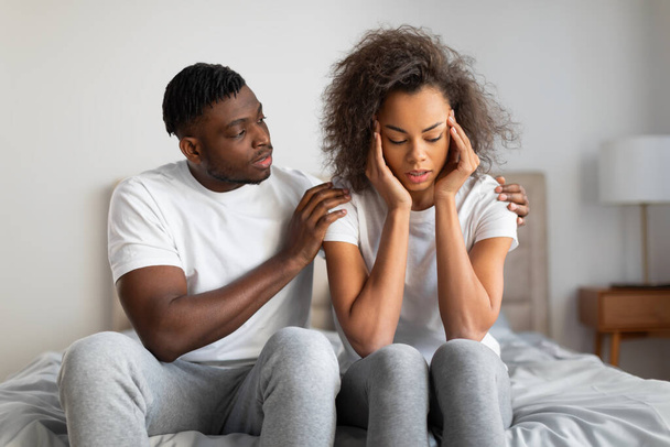 Apoyo millennial marido negro reconfortar y apoyar a su esposa deprimida en el momento de la desesperación en el dormitorio, abrazando a la mujer y diciendo buenas palabras. Concepto de desafíos de relación - Foto, imagen