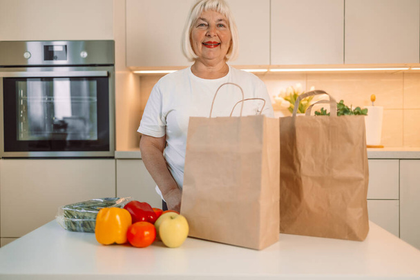 Szczęśliwa gospodyni domowa kobieta rozpakowywanie pudełka papieru w kuchni domowej, produkcji żywności ze sklepu spożywczego, uzyskanie zakupu w supermarkecie dostawy usług logistycznych. Wysokiej jakości zdjęcie - Zdjęcie, obraz