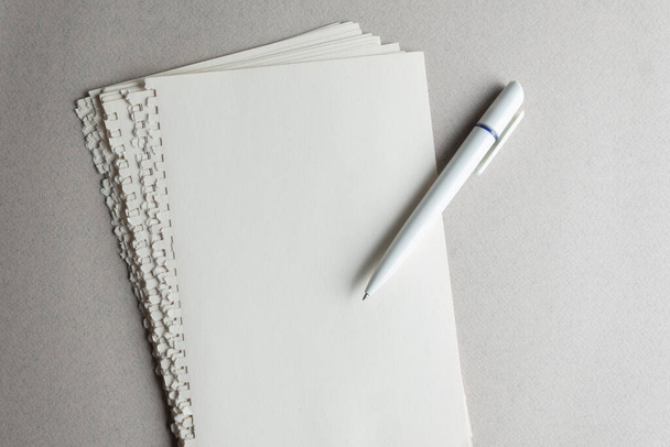 Creative Moments: Zerrissene Seiten aus einem Notizblock und einem weißen Kugelschreiber auf grauem Hintergrund. Leerzeichen für Ihre Ideen und Inspirationen! - Foto, Bild