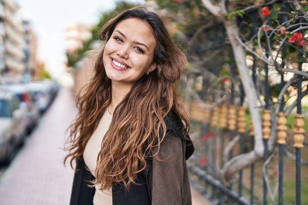 Junge schöne hispanische Frau lächelt selbstbewusst im Park - Foto, Bild