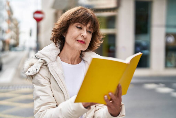 Mujer de mediana edad leyendo libro en la calle - Foto, Imagen