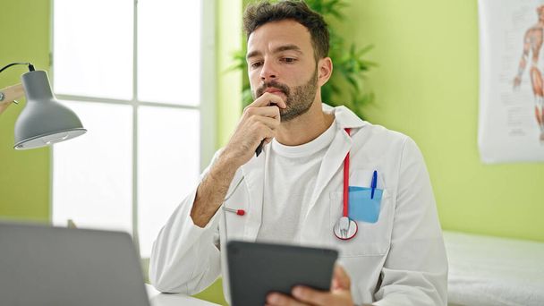 Jeune homme hispanique médecin en utilisant la pensée touchpad à la clinique - Photo, image