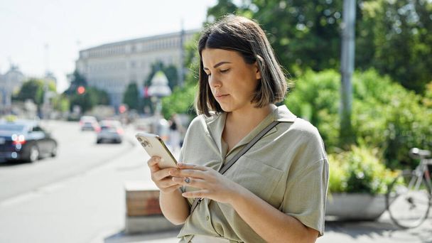 Молода красива іспаномовна жінка використовує смартфон на вулицях Відня - Фото, зображення
