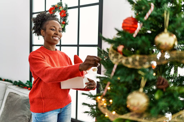 afro-américaine femme souriant confiant décoration arbre de Noël à la maison - Photo, image