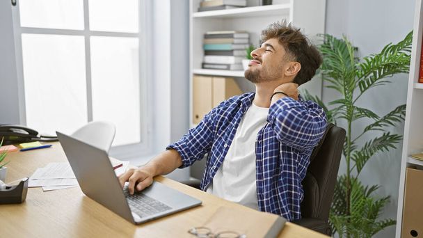Homme d'affaires arabe surmené souffrant de douleurs cervicales au bureau, jeune travailleur fatigué stressé par le travail sur Internet sur ordinateur portable. - Photo, image