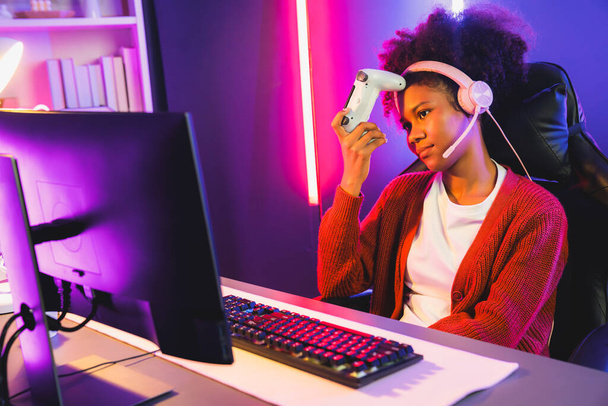 Afroamerykanka Streamer rozczarowany gry online walki z Esport wykwalifikowany zespół noszenia słuchawek w neon room. Rozmawianie z innymi graczami struganie strategii, aby wygrać konkurentów. Tastemaker. - Zdjęcie, obraz