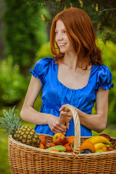 vörös hajú, mosolygó fiatal nő, egy gyümölcs-kosár - Fotó, kép