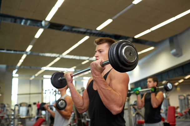 young men flexing muscles with barbells in gym - Fotoğraf, Görsel