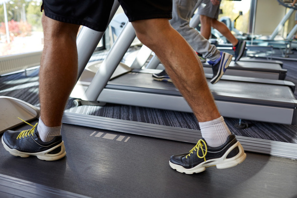 close up of men legs walking on treadmills in gym - Foto, Bild